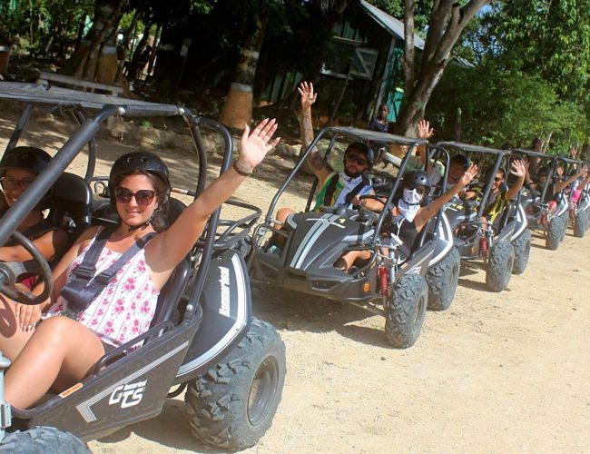 Smiling woman raising her arms during an exciting buggy ride in the Dominican countryside with Quetzal Excursions