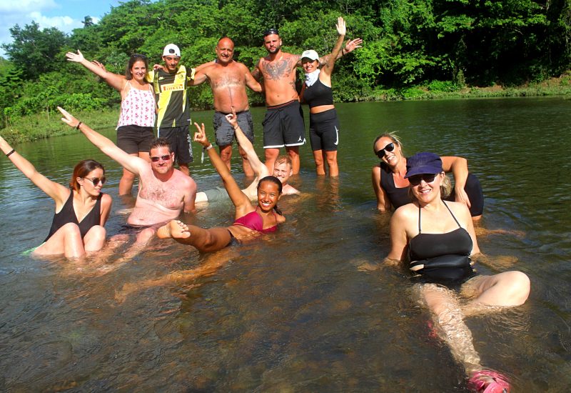 Group of travelers cooling off and smiling in the Chavón River during a cultural break on the sunset buggy excursion