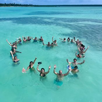 Happy group forming a heart shape in the turquoise waters of Las Palmillas natural pool — a fun and memorable moment on the Saona Economical tour by Quetzal Excursions