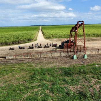 A line of buggies passing by an oil pump in the Dominican countryside during the sunset off-road tour