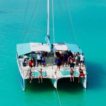 Guests relaxing on the front of the catamaran in the turquoise waters of Las Palmillas natural pool — part of the Saona Economical tour by Quetzal Excursions