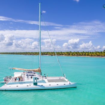 Quetzal catamaran floating on calm turquoise waters near a lush Dominican coastline