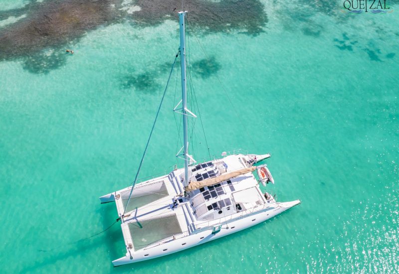 Drone shot of the Quetzal catamaran anchored in shallow turquoise water