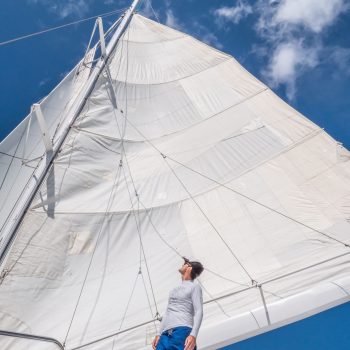 Crew member raising the sail while cruising on a sunny day in the Caribbean