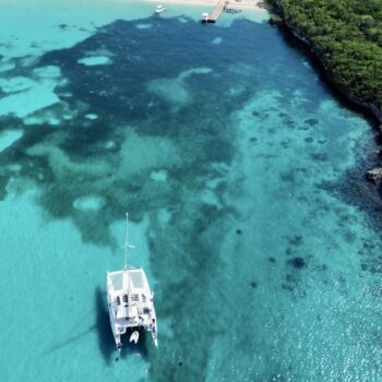 Aerial view of a catamaran floating above the coral reef and turquoise waters near Catalina Island — part of the snorkeling tour with Quetzal Excursions