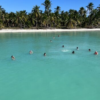 Travelers swimming and relaxing in the shallow turquoise waters of the natural pool at Las Palmillas — part of the Saona Economical tour by Quetzal Excursions