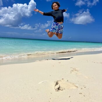 Guest jumping with joy on the white sand beach of Saona Island, enjoying a fun and memorable moment during the Saona Economical tour by Quetzal Excursions