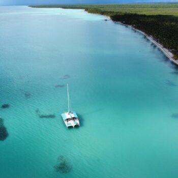 Aerial view of a catamaran anchored in the calm turquoise waters of Las Palmillas natural pool — part of the serene experience offered by Quetzal Excursions’ Saona Economical tour