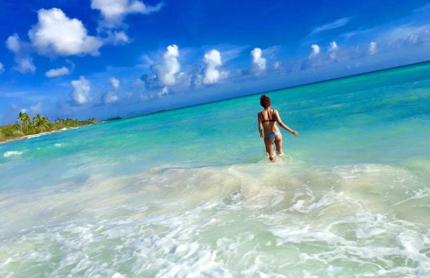 Woman walking in shallow turquoise water during a Saona Island boat tour